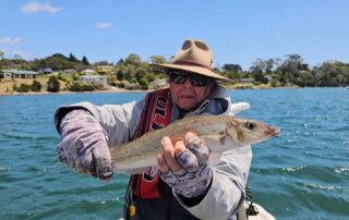 Angler in a boat on the Tamar River holding a wild trout