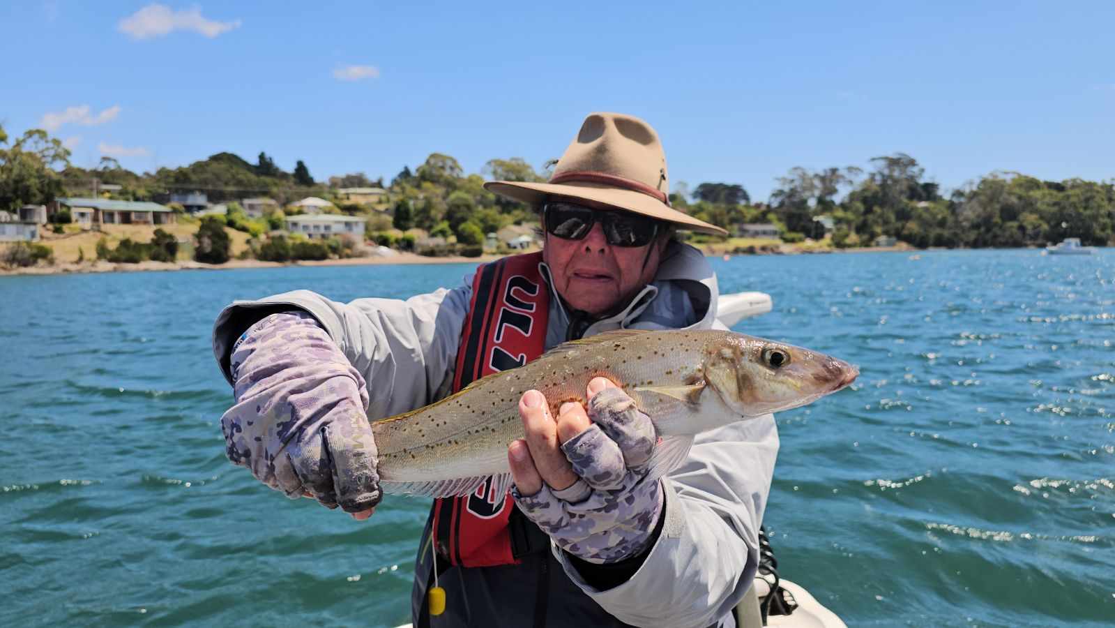 Angler in a boat on the Tamar River holding a wild trout