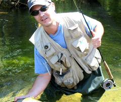 Brian holds a wild trout while standing in the water at Brumbys Creek Tasmania