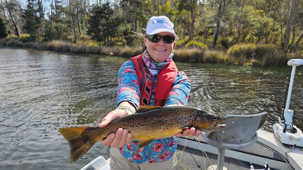 Angler holding a brown trout in a boat on a lake