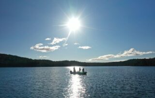 Anglers in a boat on a lake with the sun reflecting on the water