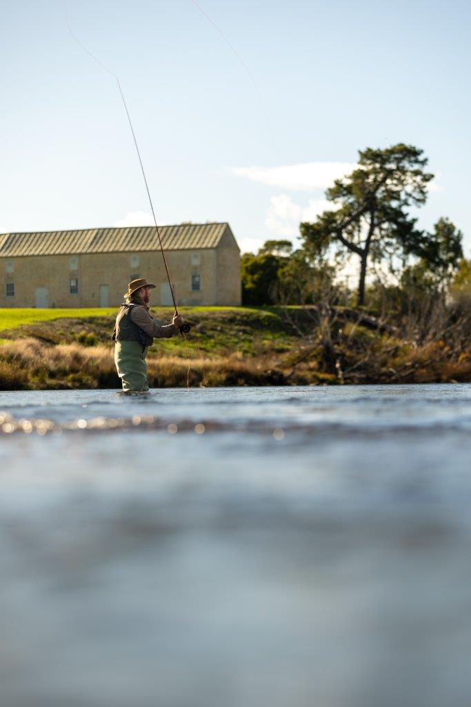 An angler standing in the river with a fly fishing rod