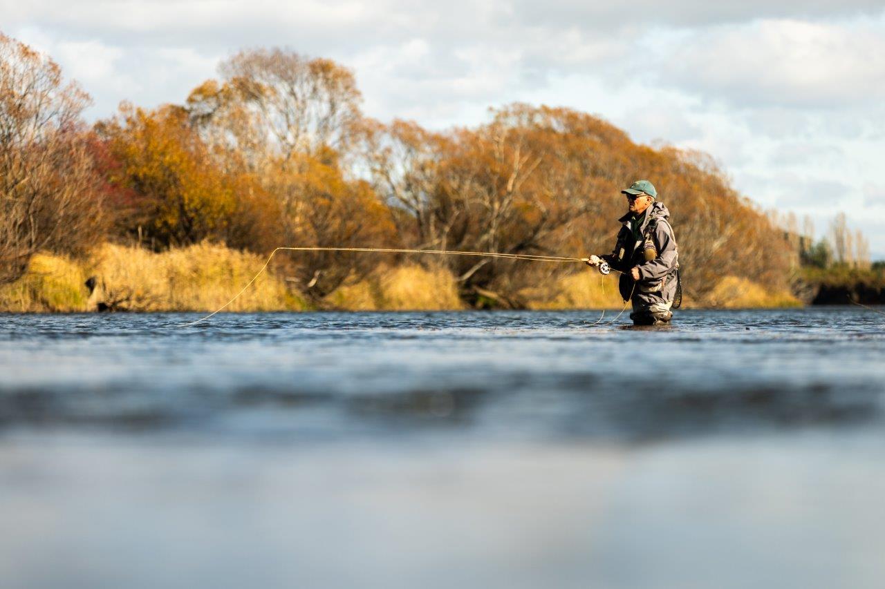 An angler standing in the river with a fly fishing rod