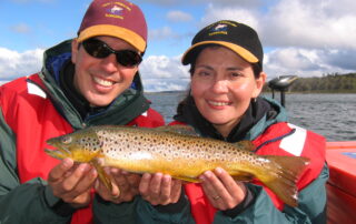 2 people holding a wild brown trout on a Tasmanian lake