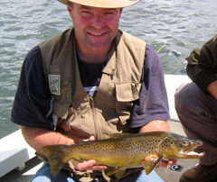 Don sitting in the boat holding a wild brown trout