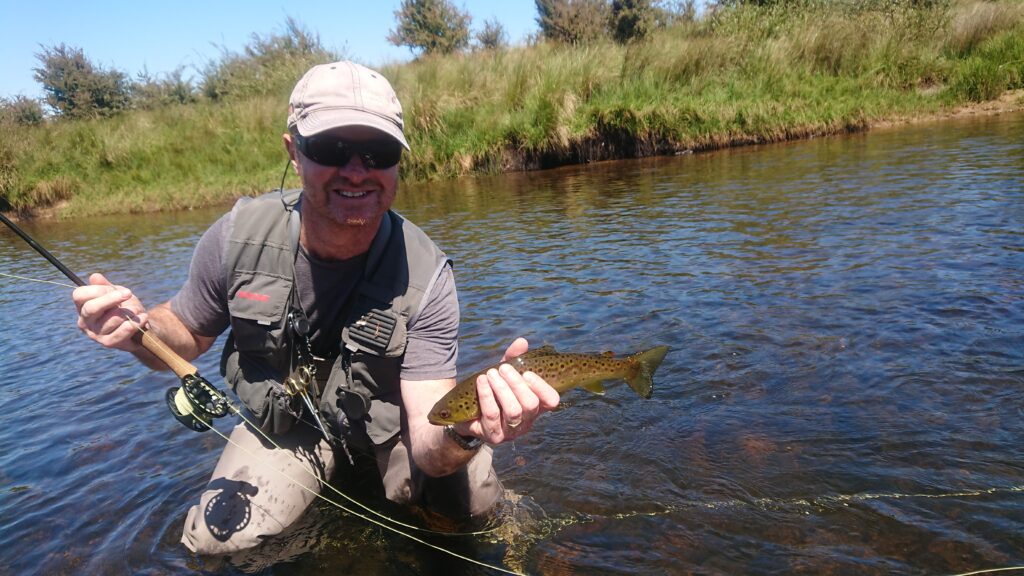 Angler with a brown trout in the water
