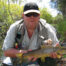 Simon holding a wild brown trout caught on a fly on a river